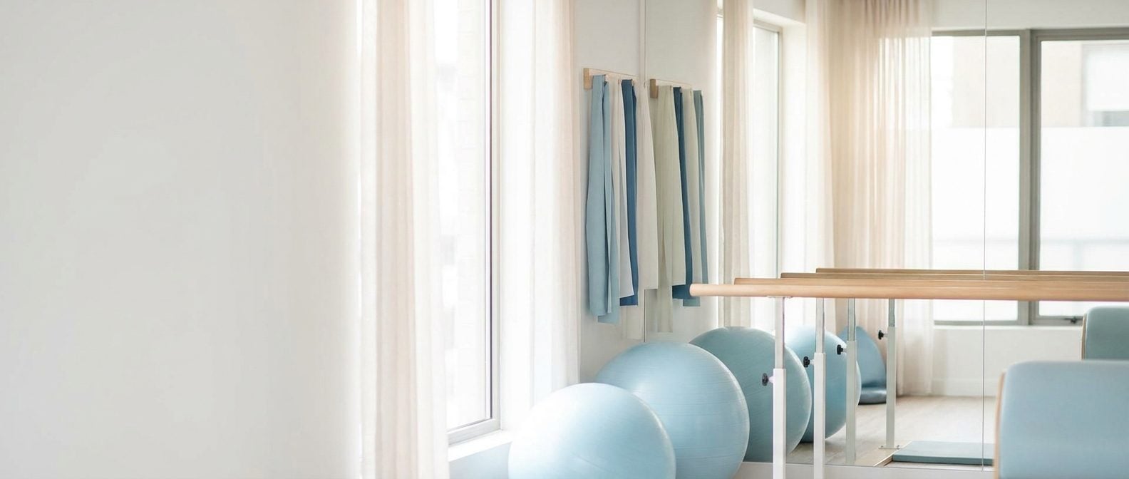 Bright physical therapy gym with exercise balls and parallel bars